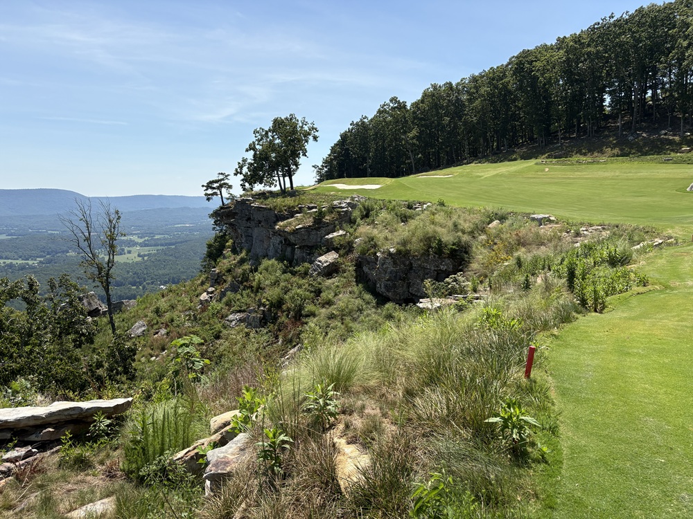 Craig Spiesman photo showing a golf green near a rocky cliff with forested valley below
