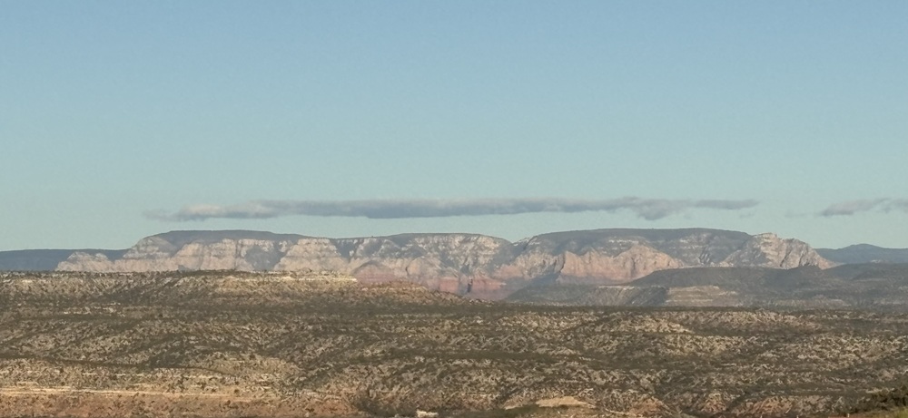 Craig Spiesman image showing broad mountain ridges with muted red and tan rock layers
