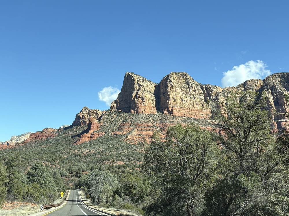 Craig Spiesman image showing a mountain road beneath rugged red and tan rock formations
